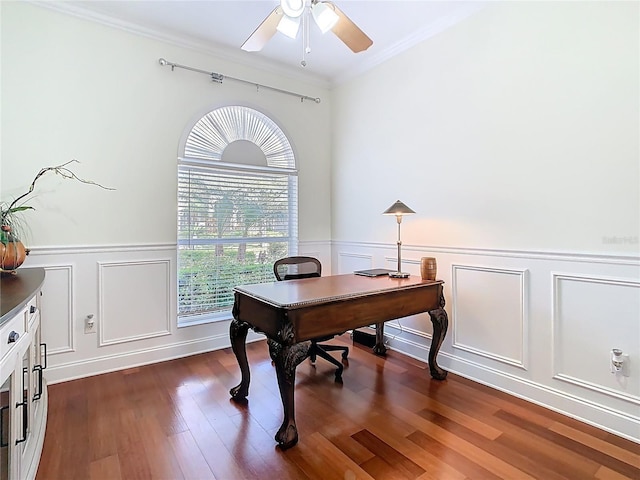 office featuring dark wood finished floors, a wainscoted wall, crown molding, and ceiling fan