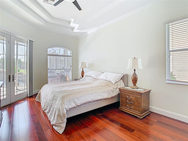 bedroom with access to exterior, french doors, a tray ceiling, and wood finished floors