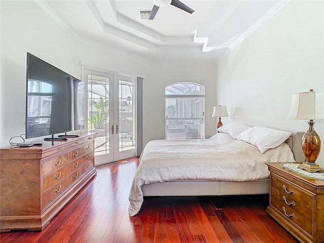 bedroom featuring access to exterior, crown molding, french doors, a raised ceiling, and wood-type flooring