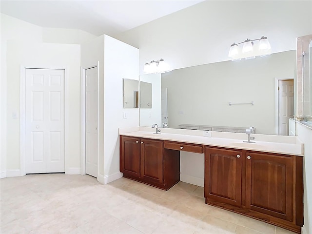 full bath featuring double vanity, baseboards, and a sink