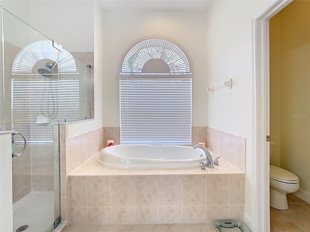 bathroom featuring toilet, a shower stall, a garden tub, and tile patterned floors