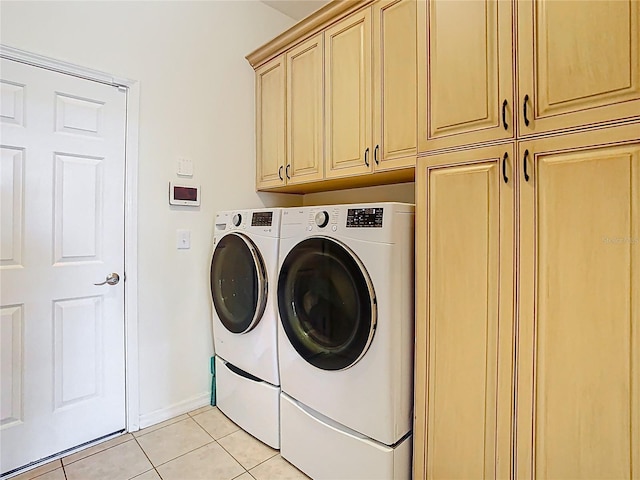 clothes washing area featuring light tile patterned floors, cabinet space, baseboards, and washing machine and clothes dryer