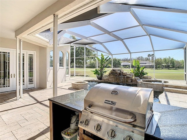 view of patio with an outdoor kitchen, an in ground hot tub, a lanai, and grilling area