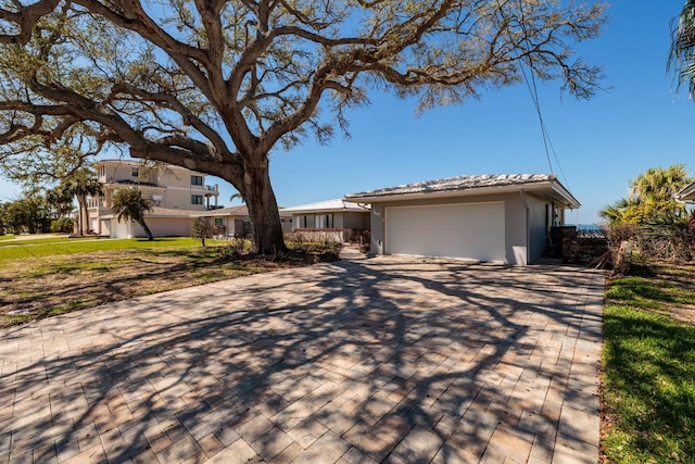 view of front facade with a tile roof, a detached garage, and stucco siding