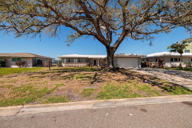 ranch-style house featuring a front yard, concrete driveway, an attached garage, and stucco siding