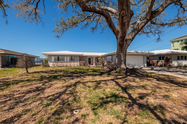 ranch-style house with concrete driveway, a front lawn, an attached garage, and fence