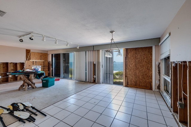 interior space featuring a textured ceiling, light tile patterned flooring, and visible vents