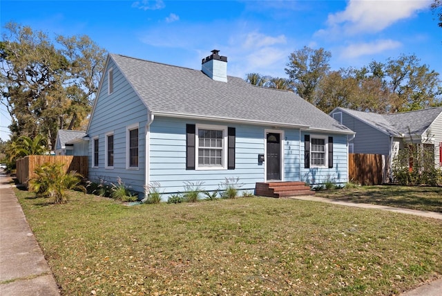 ranch-style house featuring roof with shingles, a chimney, entry steps, fence, and a front lawn