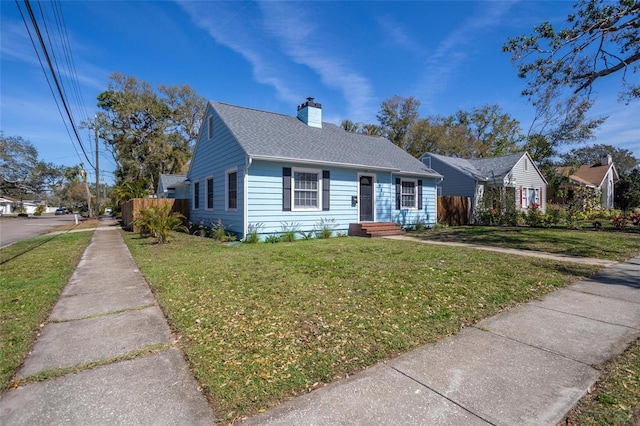 view of front facade featuring a chimney, a front lawn, and roof with shingles