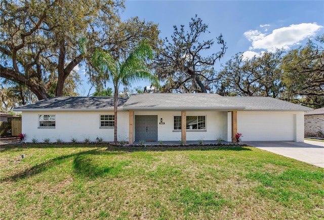 single story home featuring driveway, brick siding, an attached garage, and a front yard