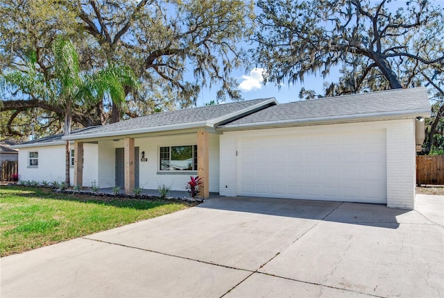 ranch-style house featuring brick siding, an attached garage, fence, driveway, and a front lawn