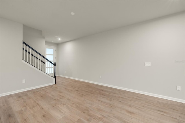 unfurnished living room featuring light wood-style flooring, recessed lighting, stairway, and baseboards