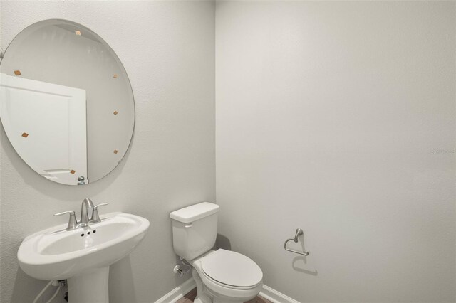 bathroom featuring baseboards, a sink, and toilet