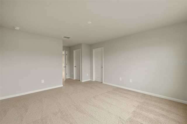 empty room featuring baseboards, visible vents, and light colored carpet