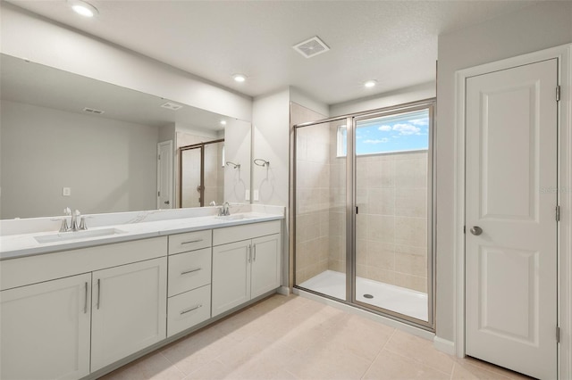 bathroom with double vanity, a sink, visible vents, and a shower stall