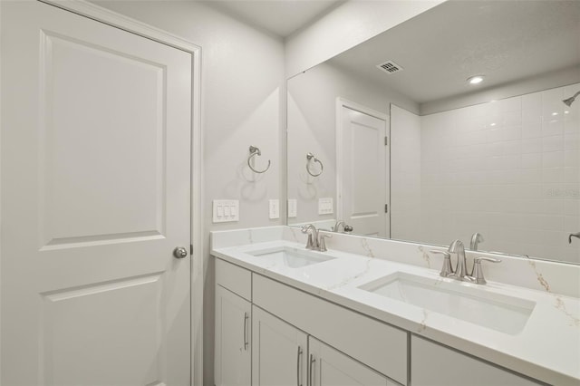 bathroom with visible vents, a sink, and double vanity