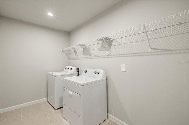 washroom featuring light tile patterned floors, laundry area, washer and clothes dryer, and baseboards