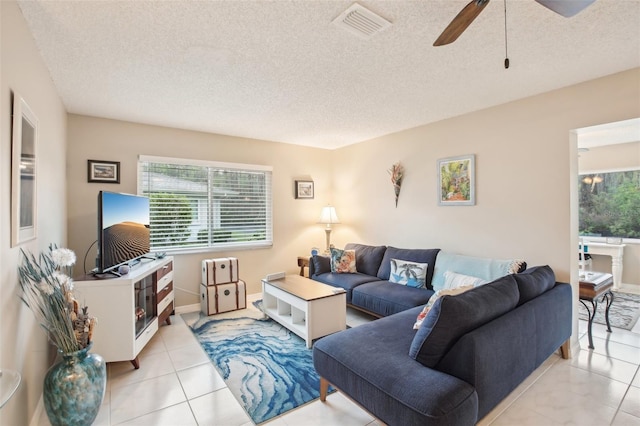 living area featuring a ceiling fan, visible vents, a textured ceiling, and light tile patterned flooring