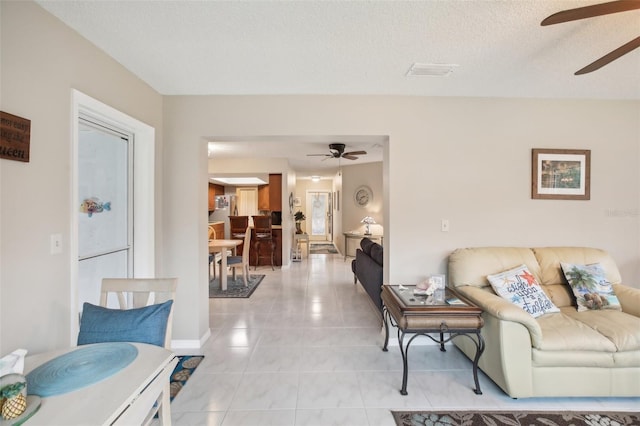 living area featuring visible vents, ceiling fan, a textured ceiling, and light tile patterned floors