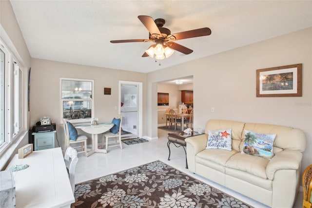 living area with tile patterned flooring, baseboards, and a ceiling fan