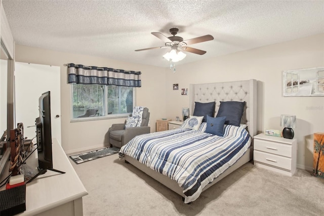 bedroom with ceiling fan, baseboards, a textured ceiling, and light colored carpet