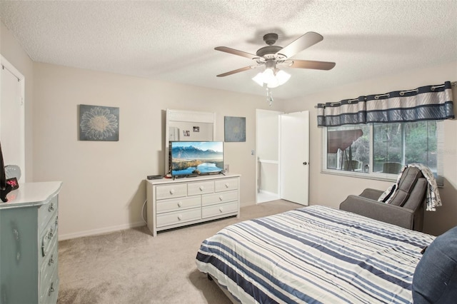 bedroom with light carpet, a textured ceiling, a ceiling fan, and baseboards