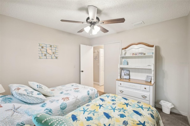 carpeted bedroom featuring a ceiling fan, baseboards, visible vents, and a textured ceiling