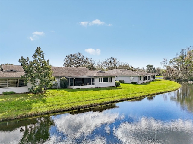 rear view of house featuring a yard, a water view, and a sunroom