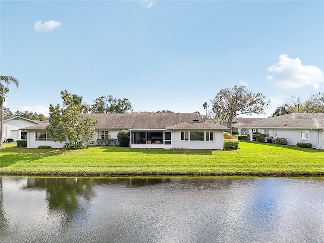 rear view of house featuring a yard, a water view, and a sunroom