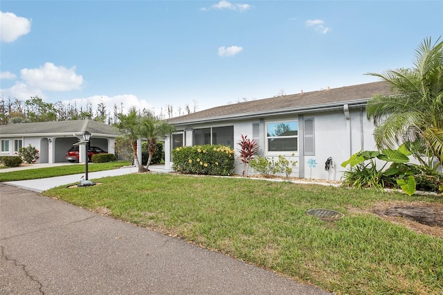 ranch-style home with driveway, a front yard, and stucco siding