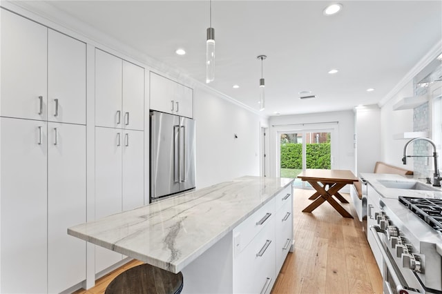 kitchen featuring premium appliances, a sink, and white cabinetry