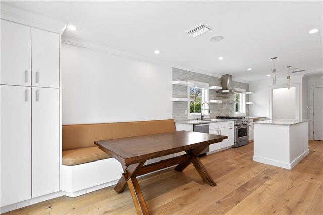 kitchen featuring open shelves, stainless steel appliances, white cabinetry, a kitchen island, and wall chimney exhaust hood