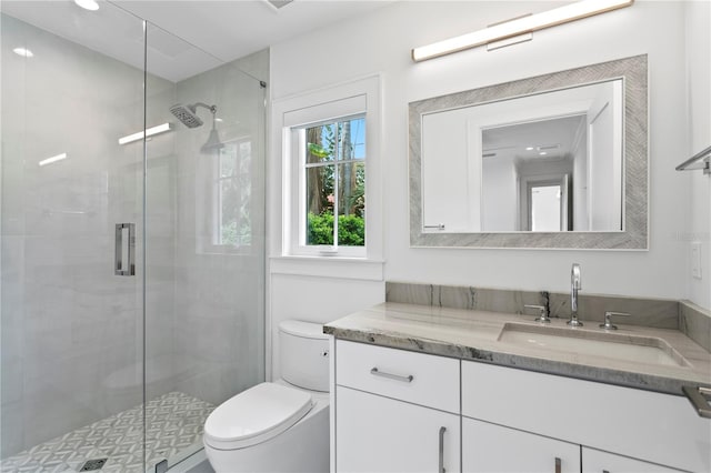 bathroom with toilet, vanity, and a shower stall