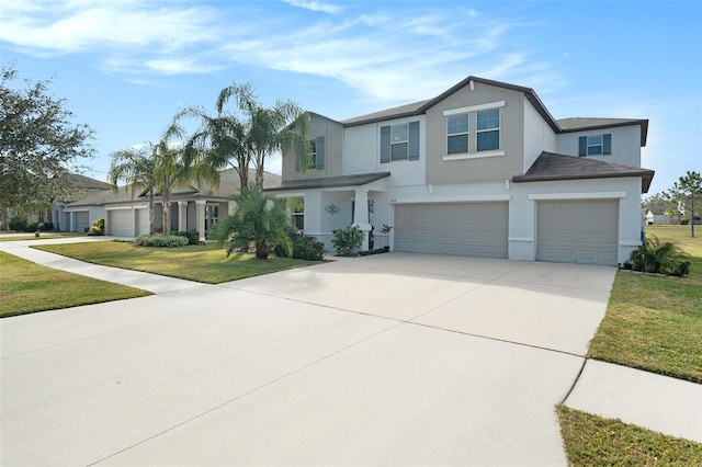 view of front of property with a garage, concrete driveway, a front lawn, and stucco siding