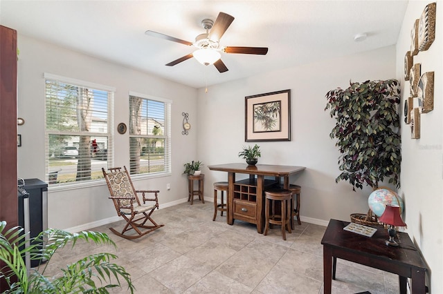 living area featuring a ceiling fan and baseboards