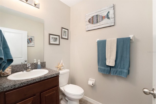 bathroom featuring baseboards, vanity, and toilet