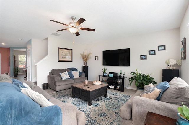 living area with a ceiling fan, light colored carpet, visible vents, and baseboards