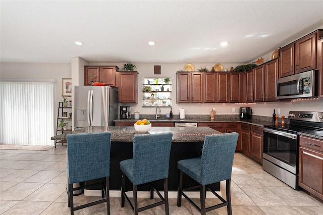 kitchen featuring light tile patterned floors, appliances with stainless steel finishes, a breakfast bar, and a center island