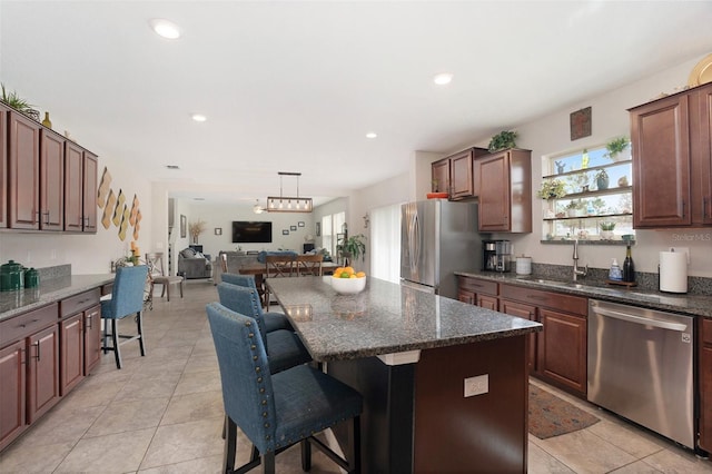 kitchen with appliances with stainless steel finishes, open floor plan, a healthy amount of sunlight, and a sink