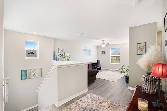 corridor with baseboards, visible vents, an upstairs landing, and wood finished floors