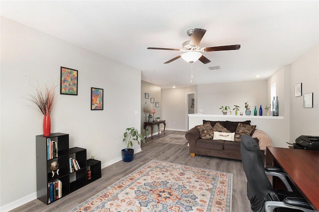 living room featuring baseboards, wood finished floors, visible vents, and a ceiling fan