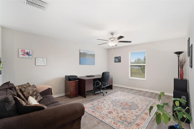 office featuring light wood finished floors, baseboards, visible vents, and a ceiling fan