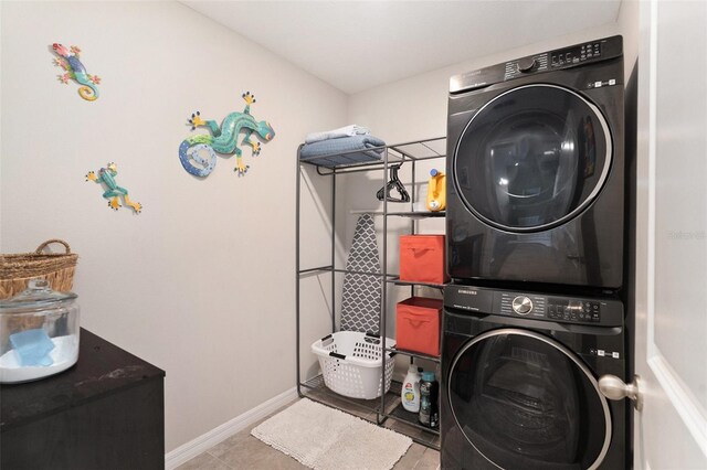 clothes washing area with laundry area, stacked washer and clothes dryer, baseboards, and tile patterned floors