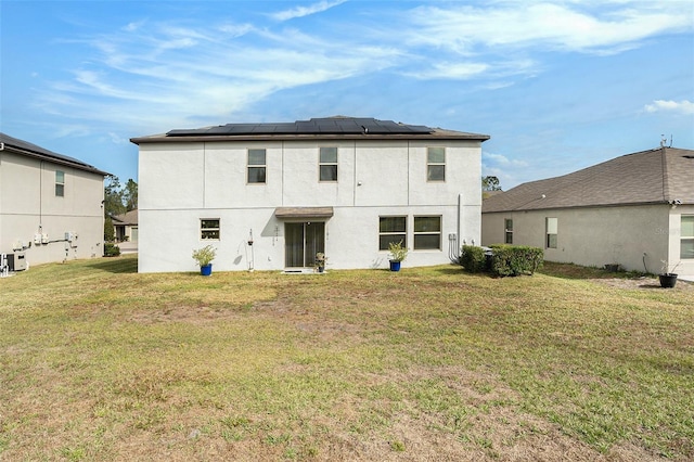 back of property featuring a lawn, stucco siding, and roof mounted solar panels