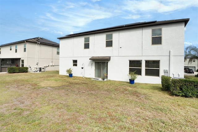 back of house featuring a lawn and stucco siding