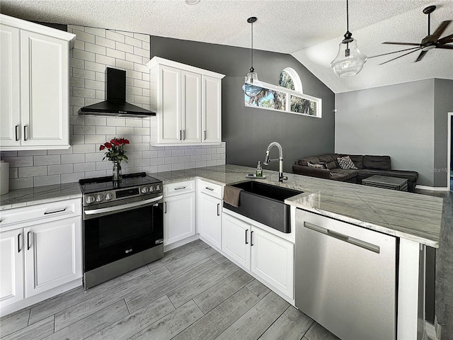 kitchen featuring stainless steel appliances, white cabinets, a sink, wall chimney range hood, and a peninsula