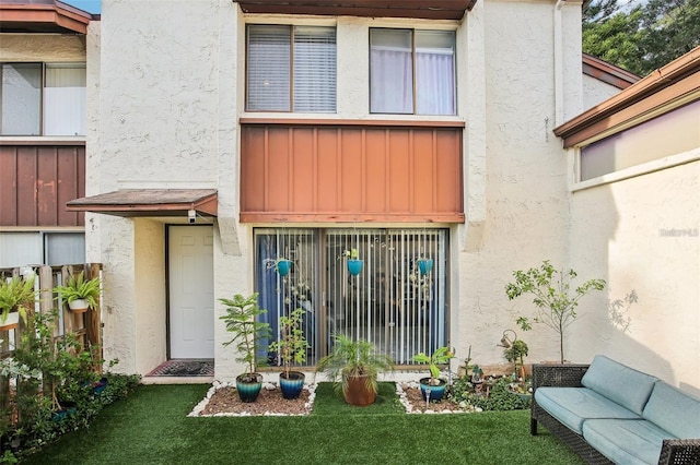 property entrance with a lawn and stucco siding