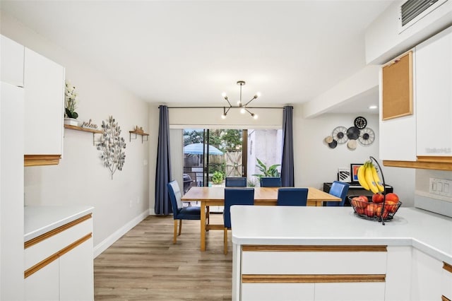 dining space featuring light wood-style floors, baseboards, visible vents, and an inviting chandelier