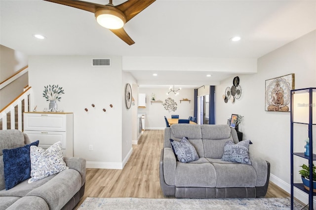 living room with stairs, baseboards, visible vents, and light wood-style floors