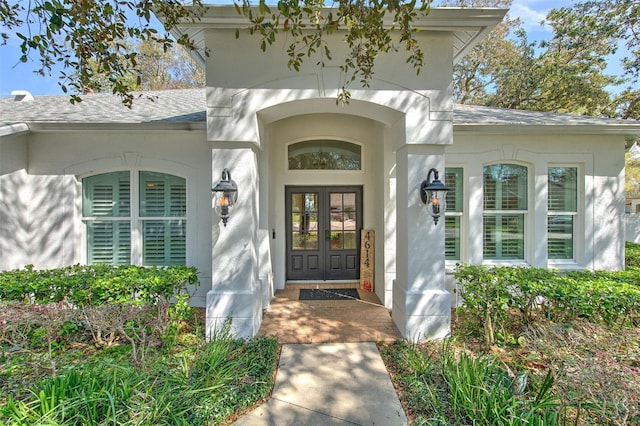 doorway to property featuring stucco siding, roof with shingles, and french doors